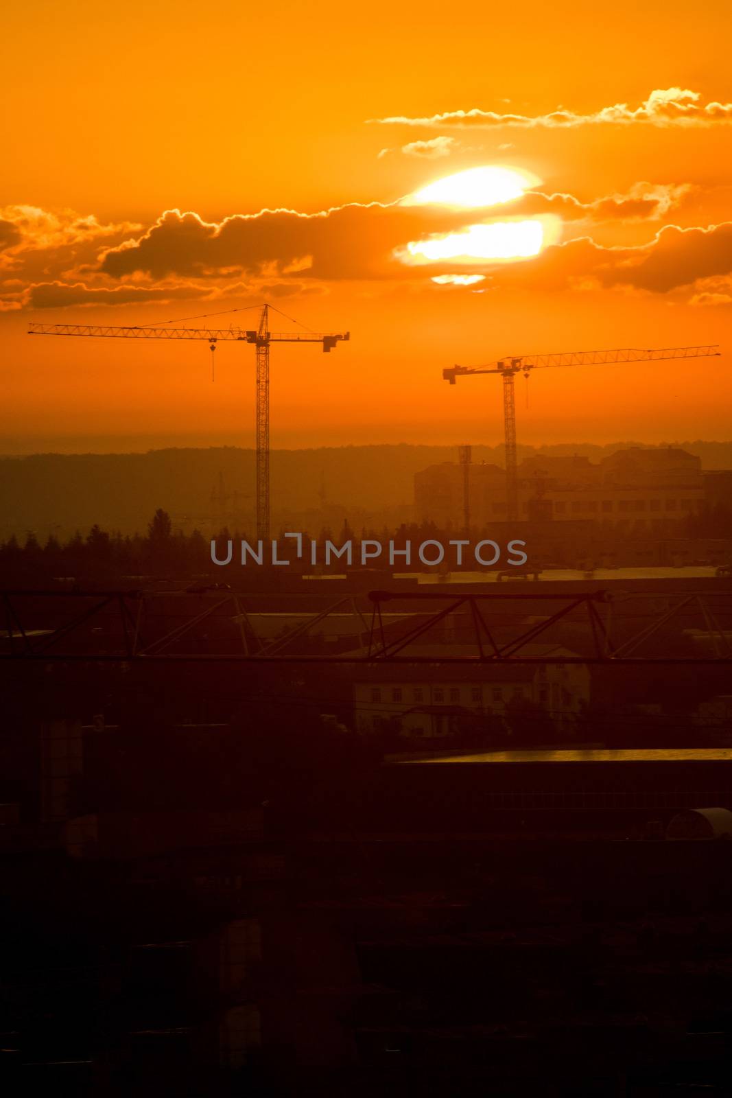 Bright orange sunset shines on the industrial construction site. Mid shot