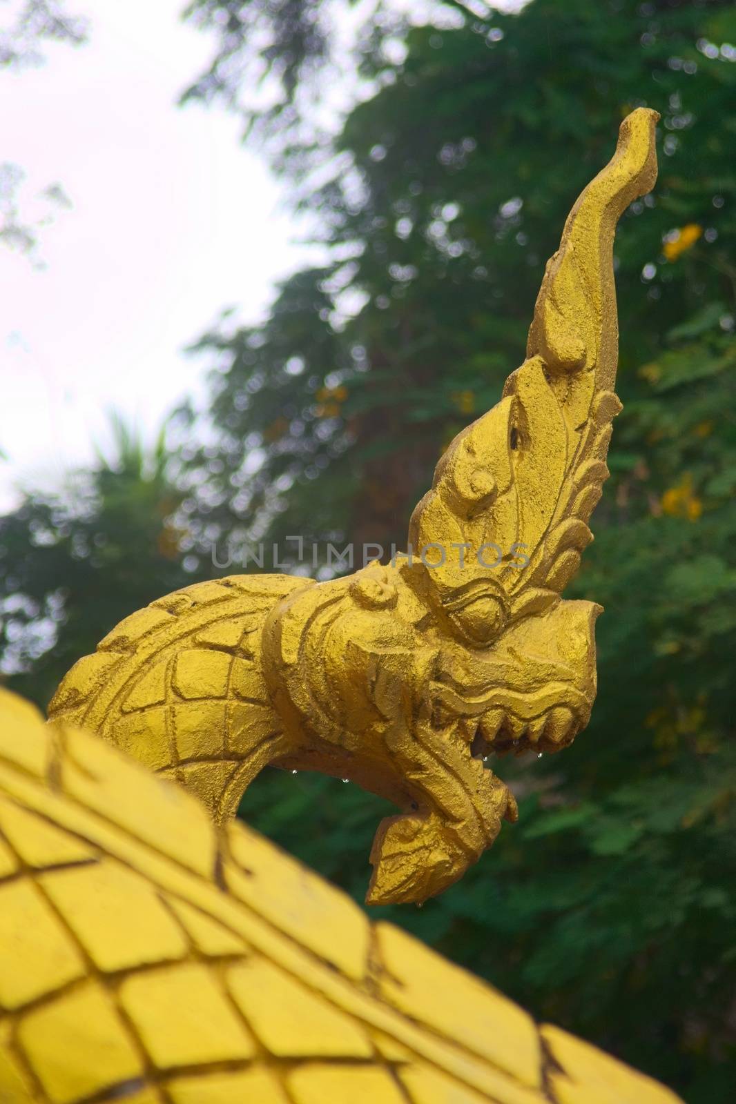 Gilded sculpture of a Naga serpent, a mythological protector creature, at the entrance of a Buddhist temple in Luang Prabang, Laos.