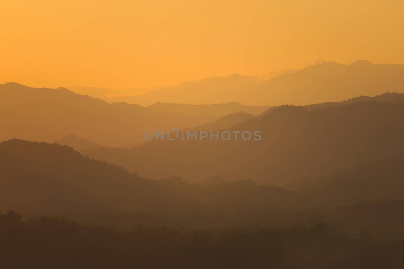 Orange sky over hazy mountains around Luang Prabang, Laos. View from the top of Mount Phou Si. by hernan_hyper