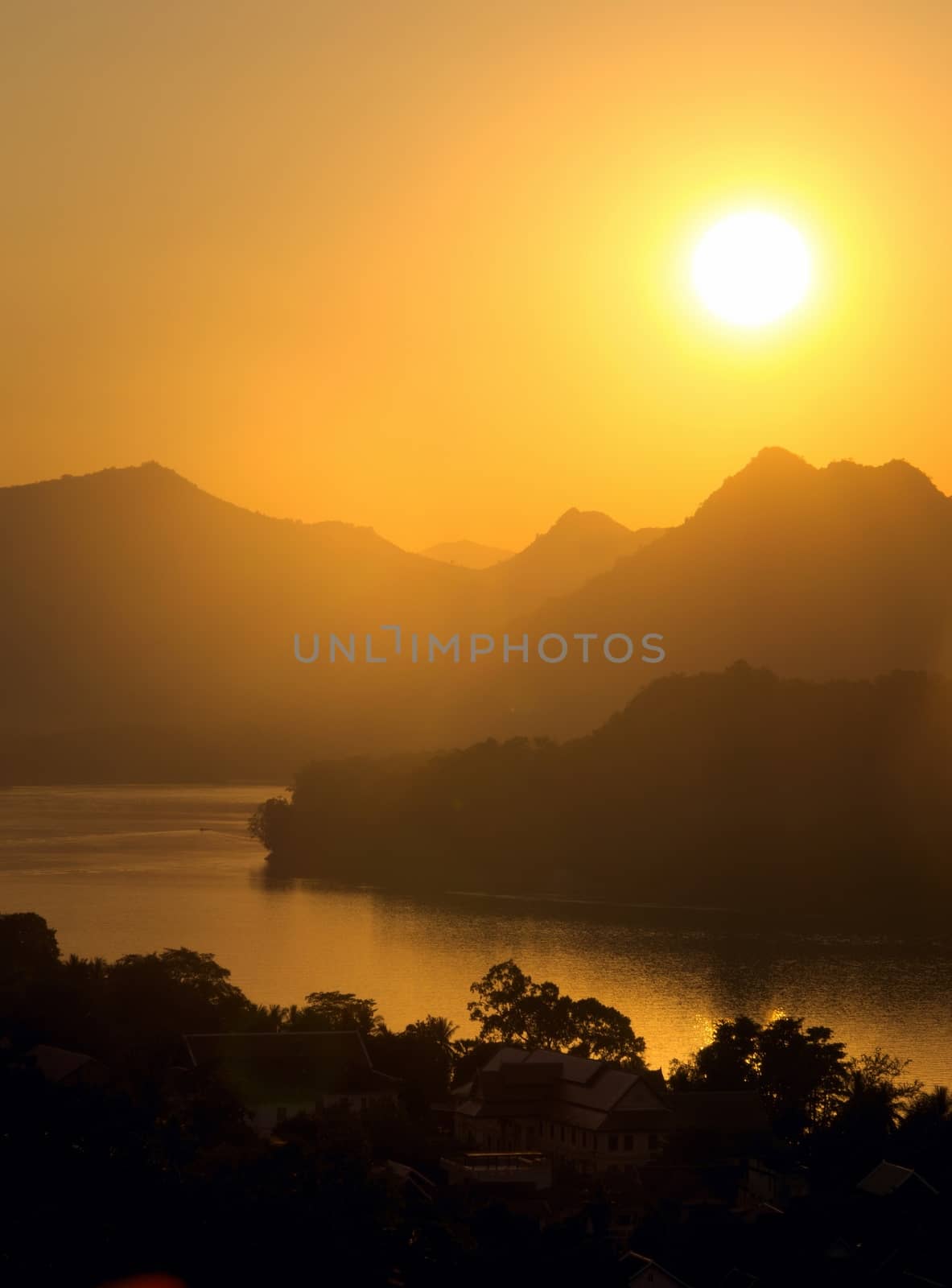 Sunset over hazy mountains by the Mekong river. View from Mount Phou Si, in Luang Prabang, Laos.