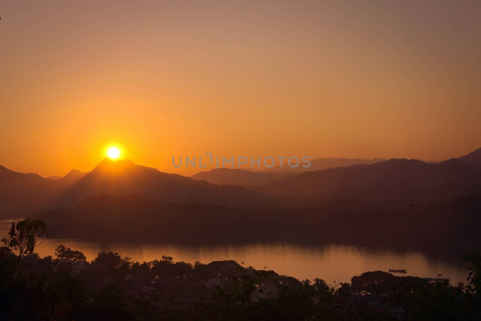 Glorious sunset over hazy mountains by the Mekong river. View from Mount Phou Si, in Luang Prabang, Laos. by hernan_hyper