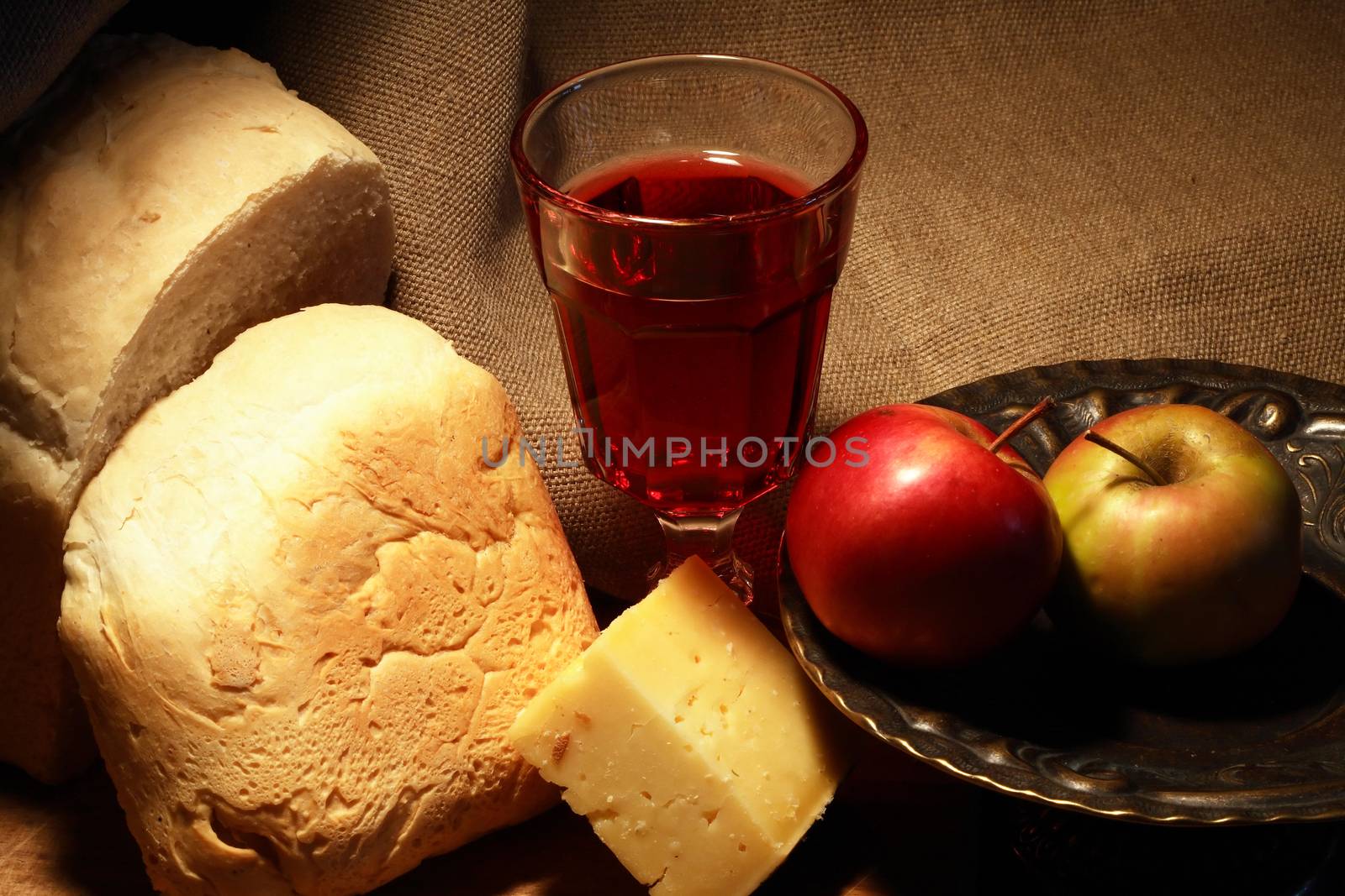 Loaf of white bread near cheese and fruits on canvas background