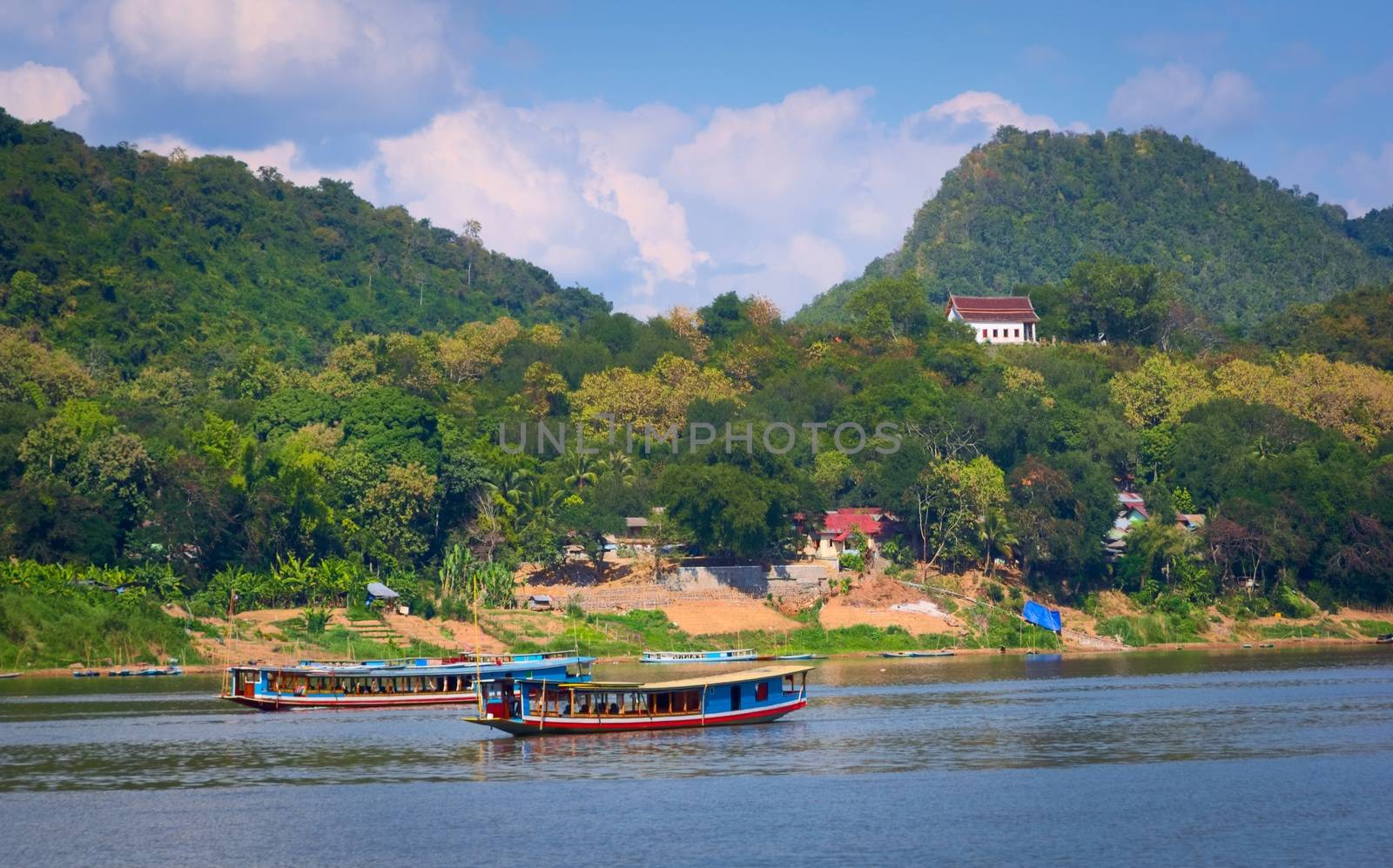 Long boats and barges sailing the Mekong River near Luang Prabang, Laos. by hernan_hyper