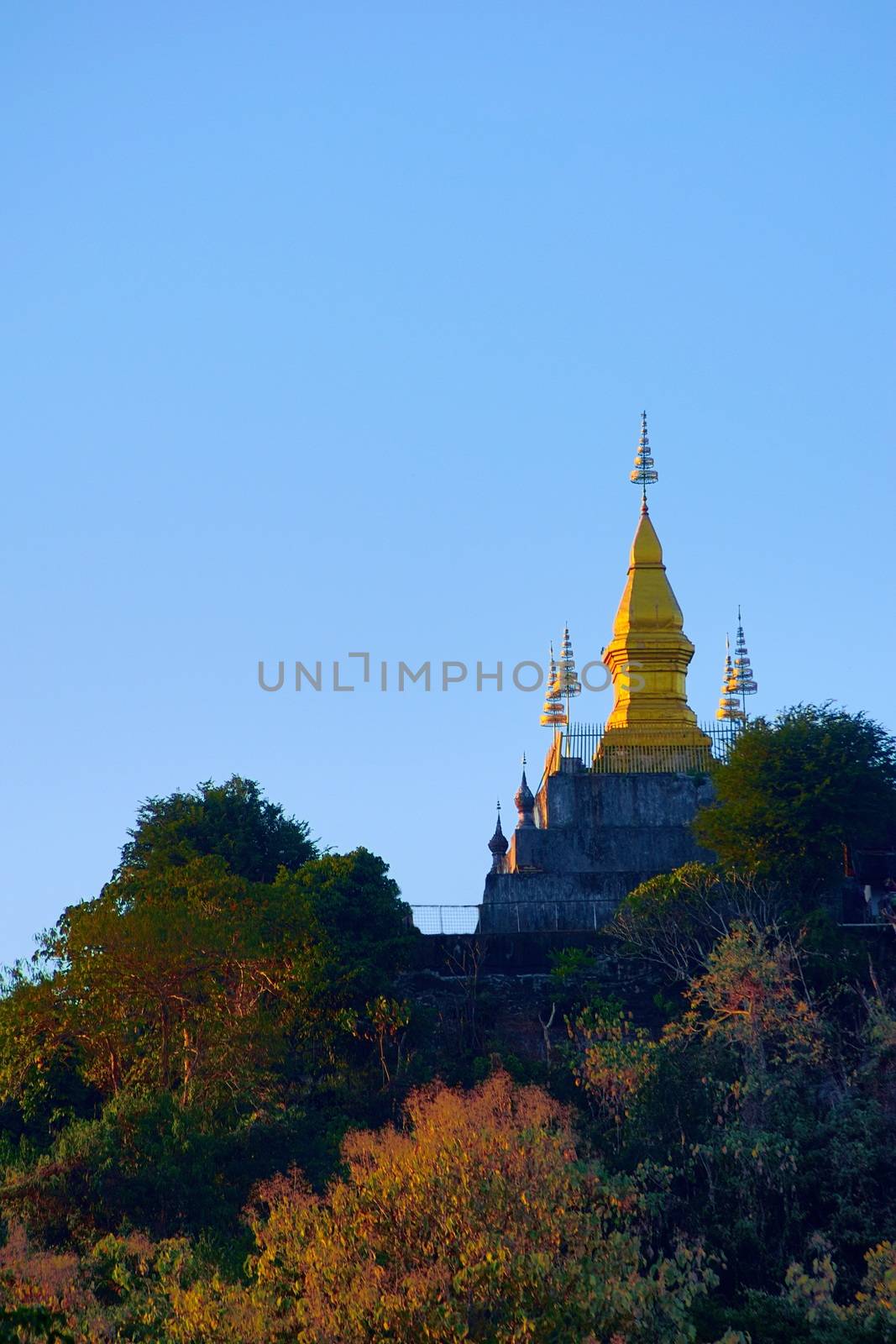 Golden buddhist stupa of Wat Chom Si at the summit of Mt. Phou Si, in Luang Prabang, Laos. Low angle view from the city. by hernan_hyper