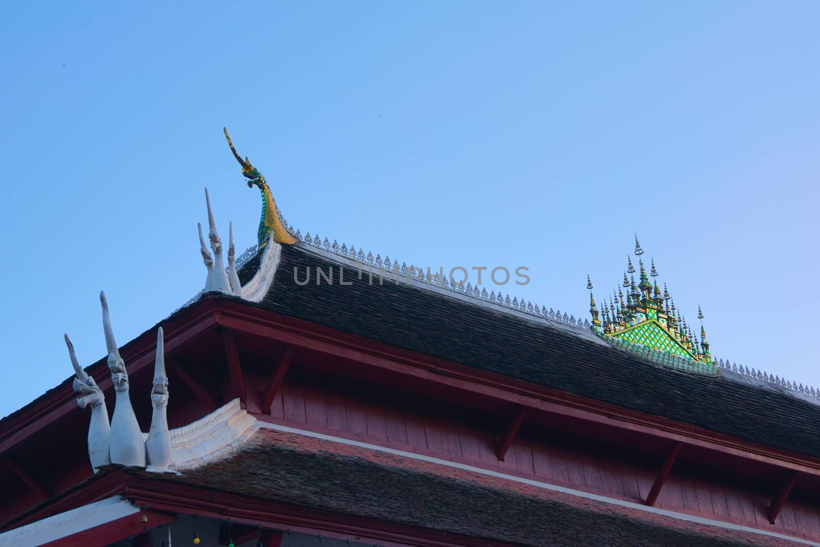 Buddhist temple of Wat Wisunarat in Luang Prabang, Laos. Architectural detail of the Naga serpents on the soffit and glass mosaic ornament on top.