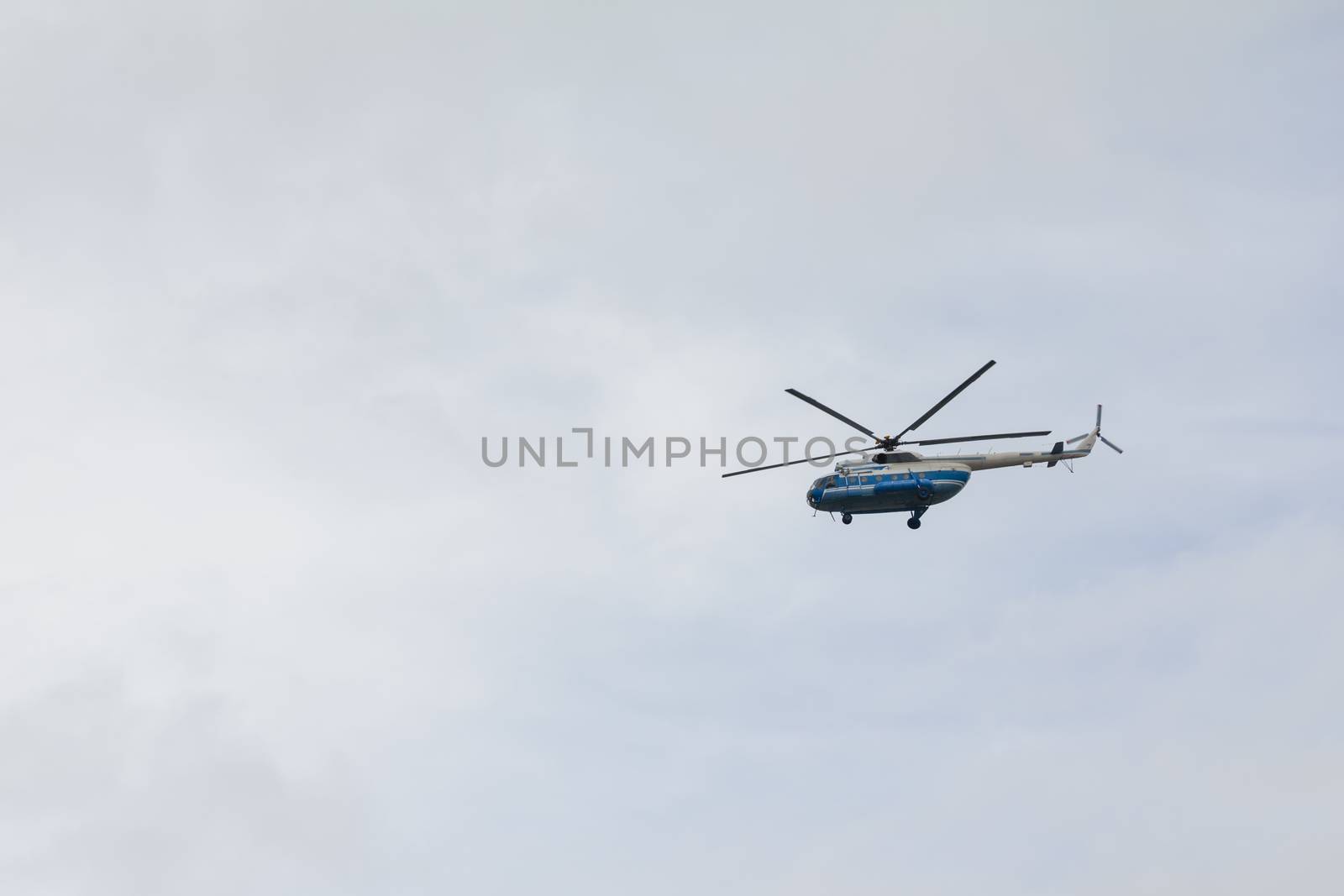 Helicopter high flying at the gray sky by Studia72