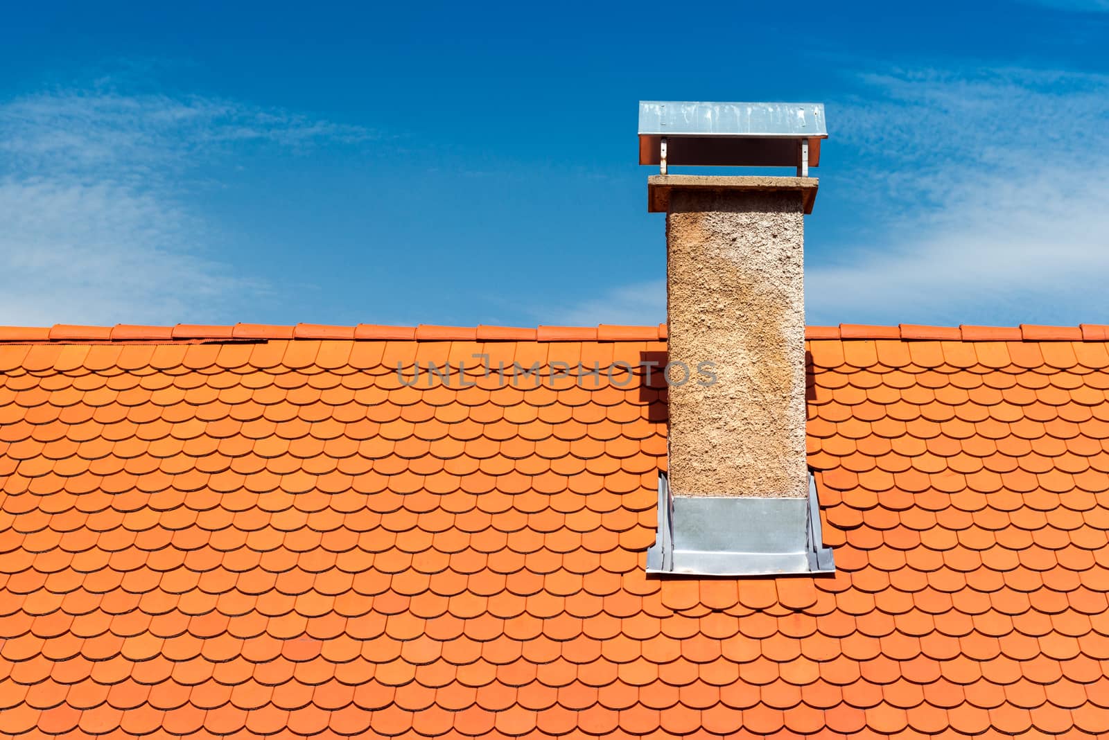 Modern roof with chimney. Orange ceramic tile, shingle. Blue sky on the background