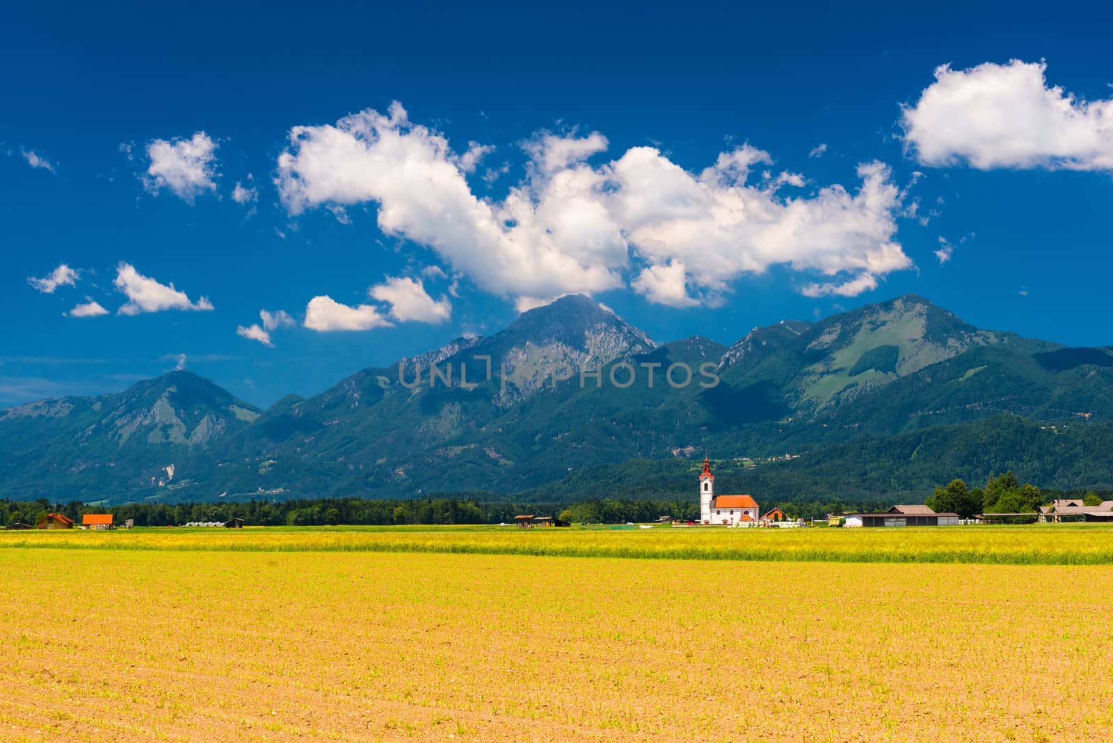Beautiful landscape panorama. Blue sky with clouds. Lonely Church in the field with mountains and hills on the background.