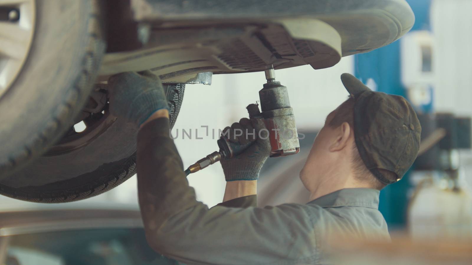 Mechanic unscrews detail of car in hood - automobile service repairing, close up view