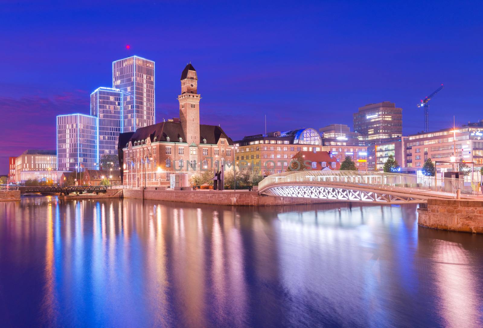 A view of a city at night. An evening panorama of Malmo is reflected on the water, Sweden. Long exposure photo with smooth nice reflections