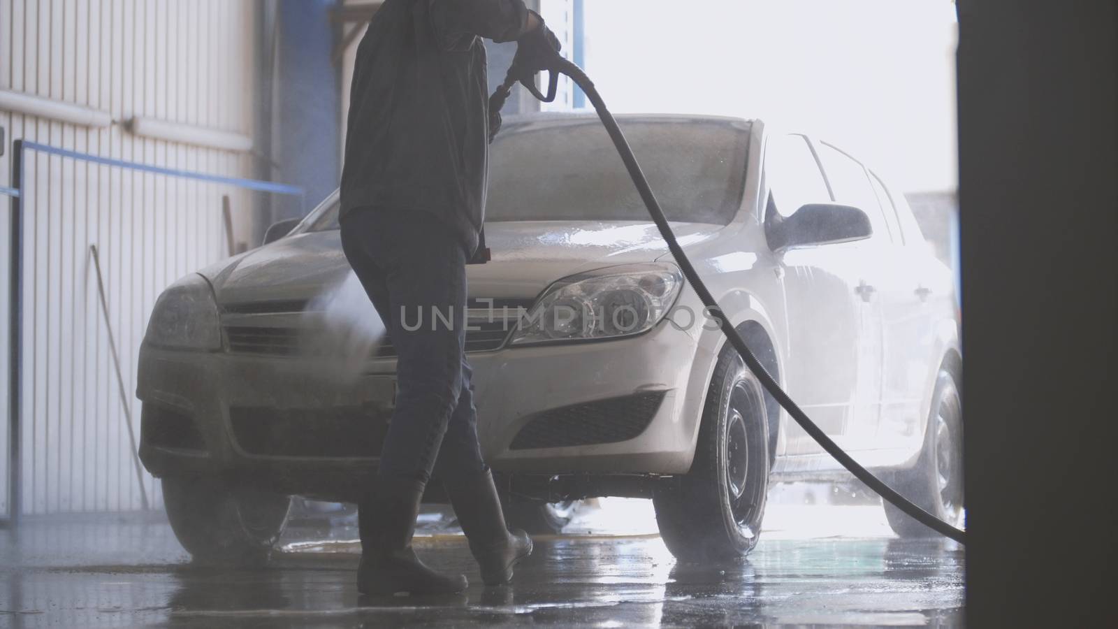Woman worker with the water hose in car-washing facility by Studia72