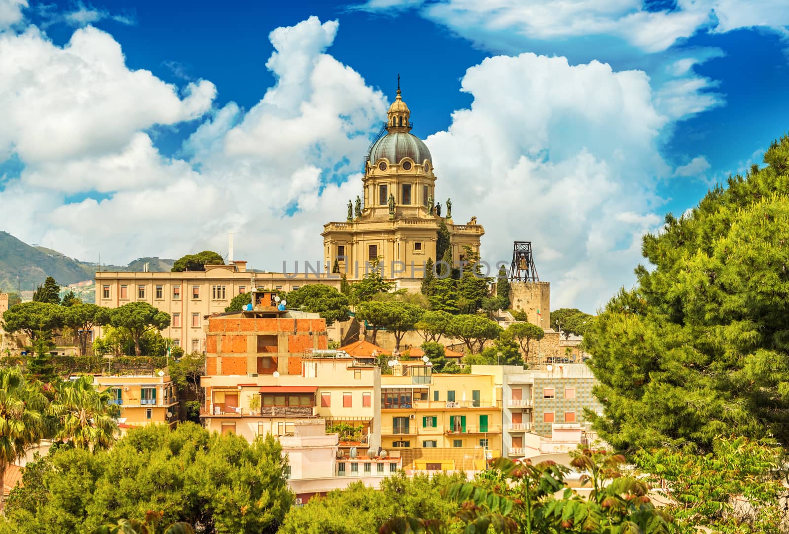 Cityscape of Messina with Cathedral on the top of the hill, colored houses and beautiful clouds with a blue sky, Sicily, Italy