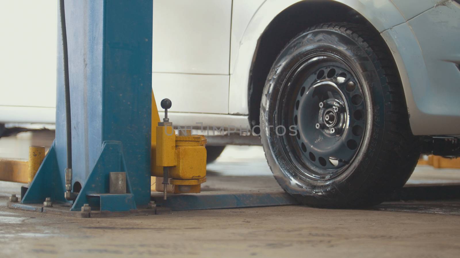 Car in auto service lifting for repairing, mechanics in garage, close up