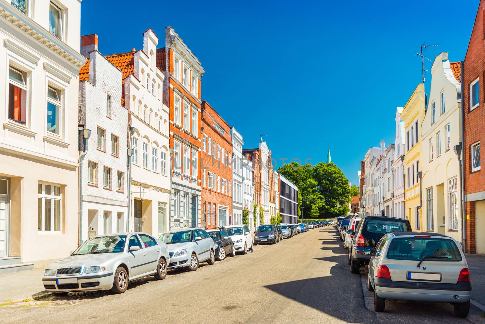 View of an empty street in Lubeck, Germany. Row of residential houses and cars parked along the street