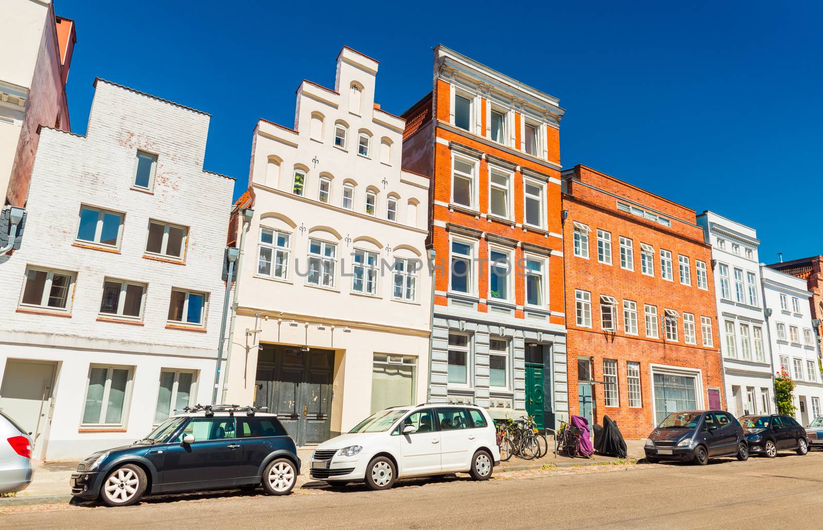 A street of an old German town. Modern cars parked near a row of different historical buildings. Lubeck, Germany