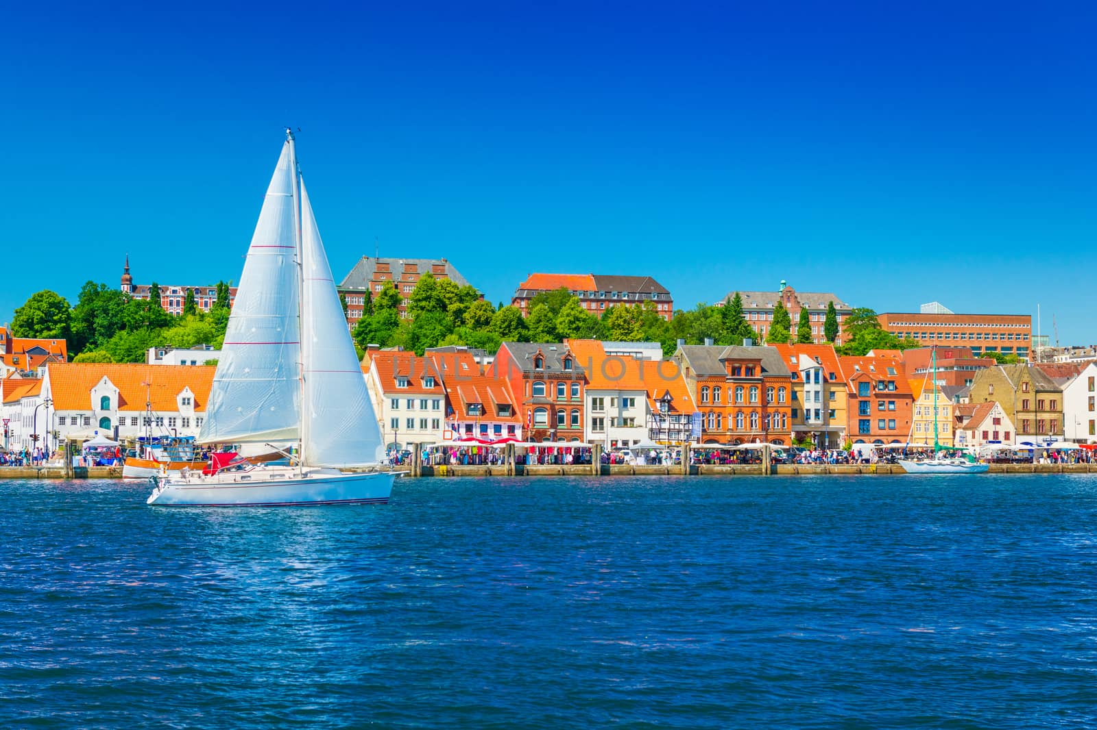 Beautiful panorama of a European port city. A yacht is sailing against the skyline of the city of Flensburg, Germany