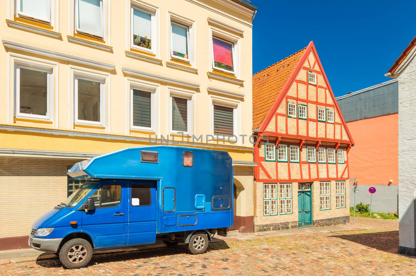 Flensburg - July 2018, Germany: Blue motorhome parked near a modern building and an old house in the traditional German style, view of a street in Flensburg (Some original elements were removed)