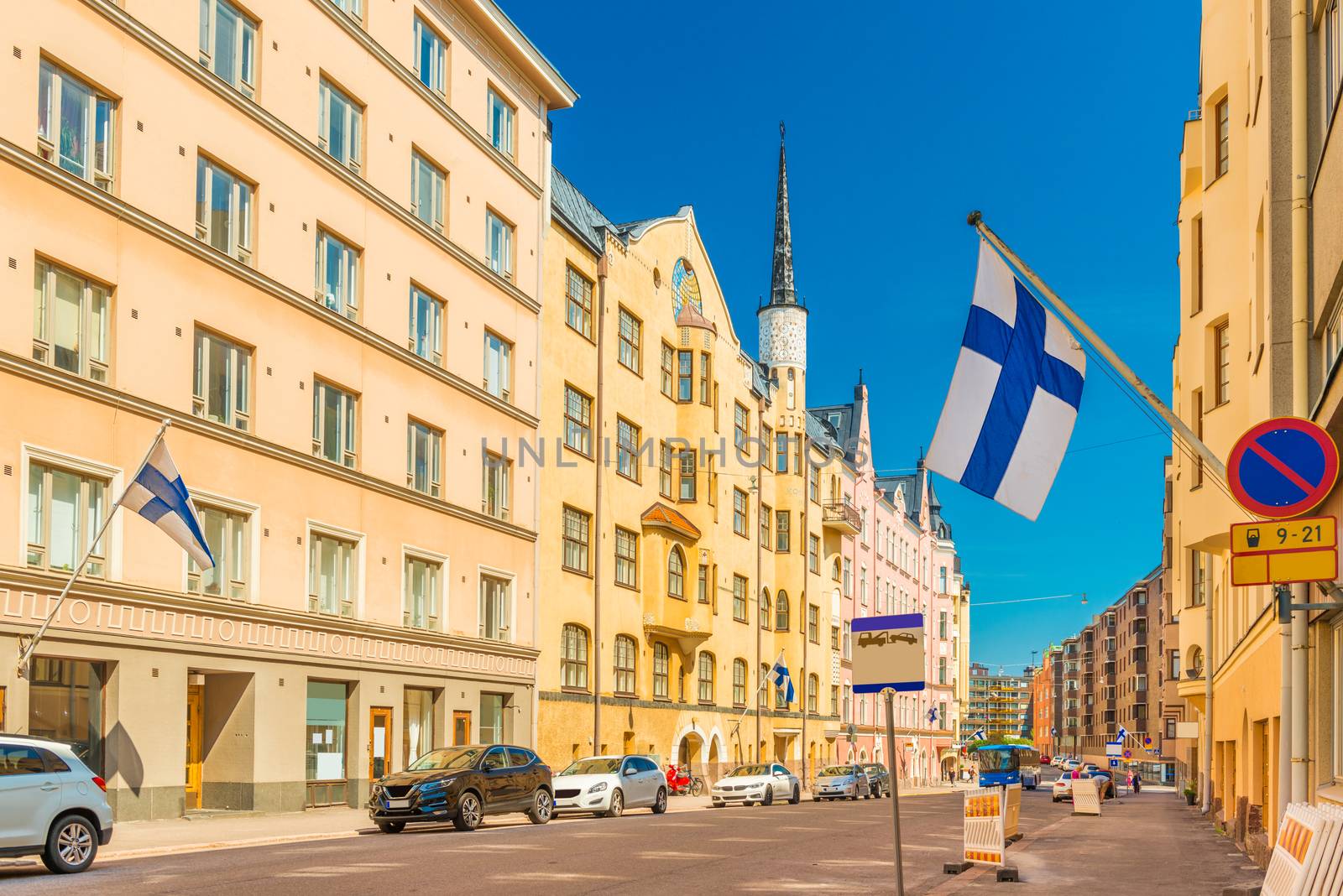 A beautiful street in Helsinki with colorful historical buildings with Finnish flags on the facades, Finland