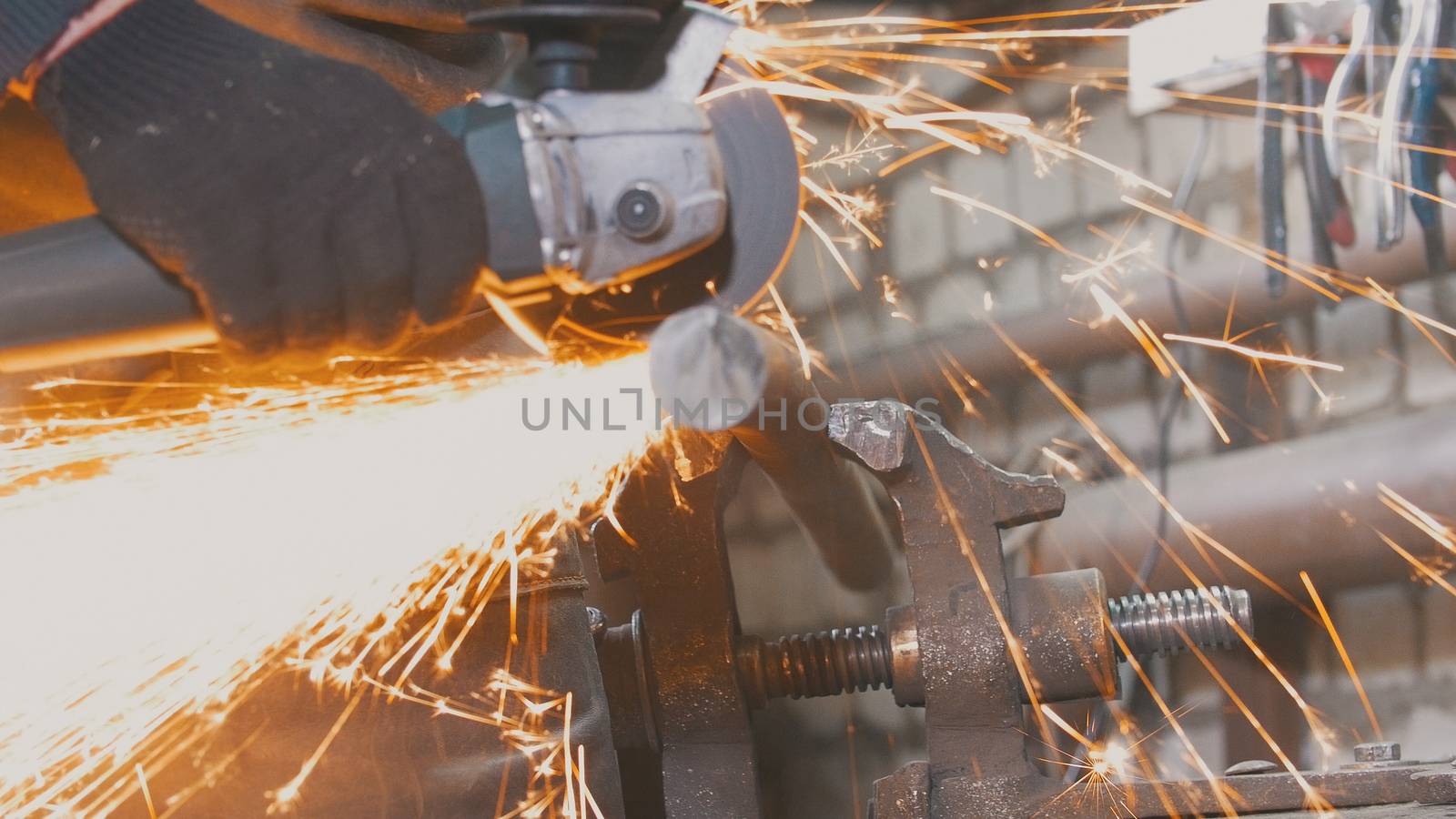 Blacksmith worker in forg making detail with circular saw, close up