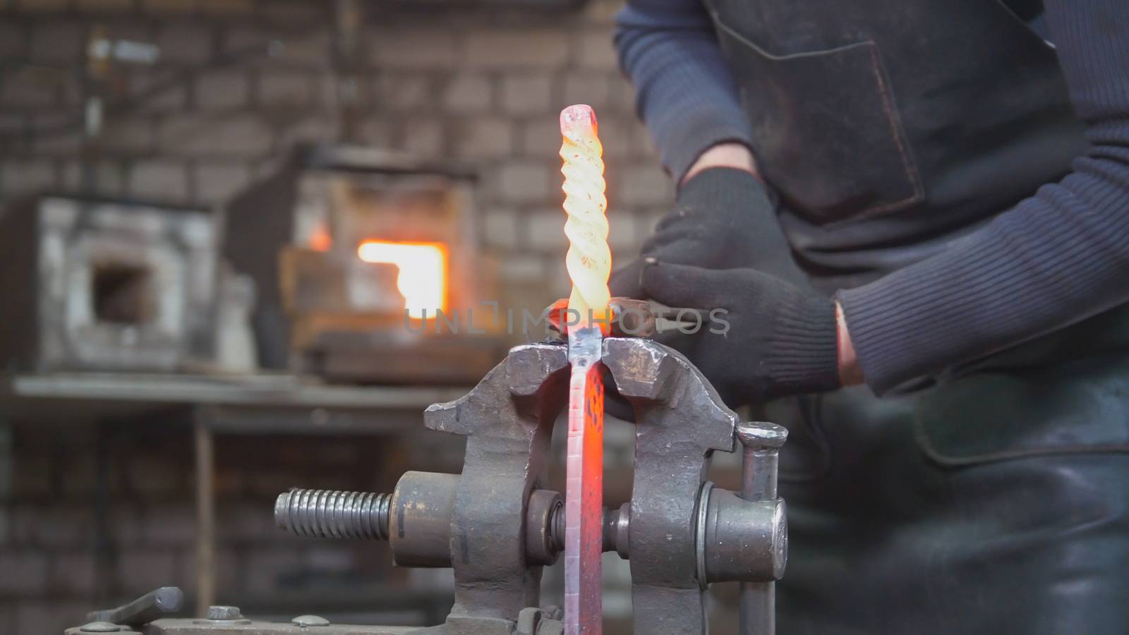 Close up view - hands of Blacksmith with gloves in forge makes steel knife, small business