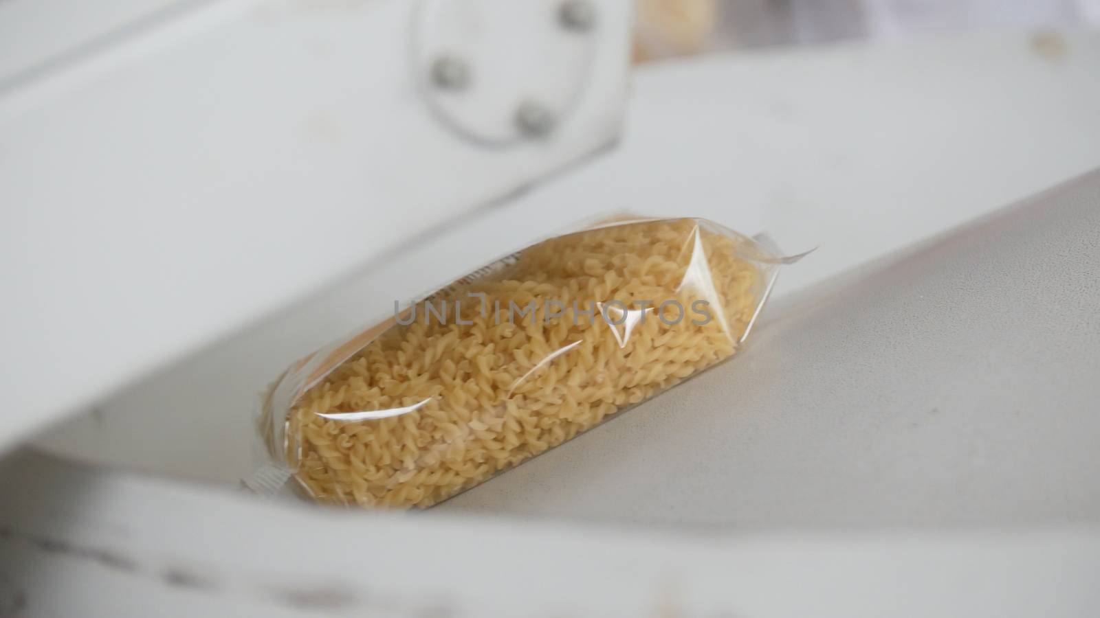 Worker packaging raw macaroni in a pasta manufactury by Studia72