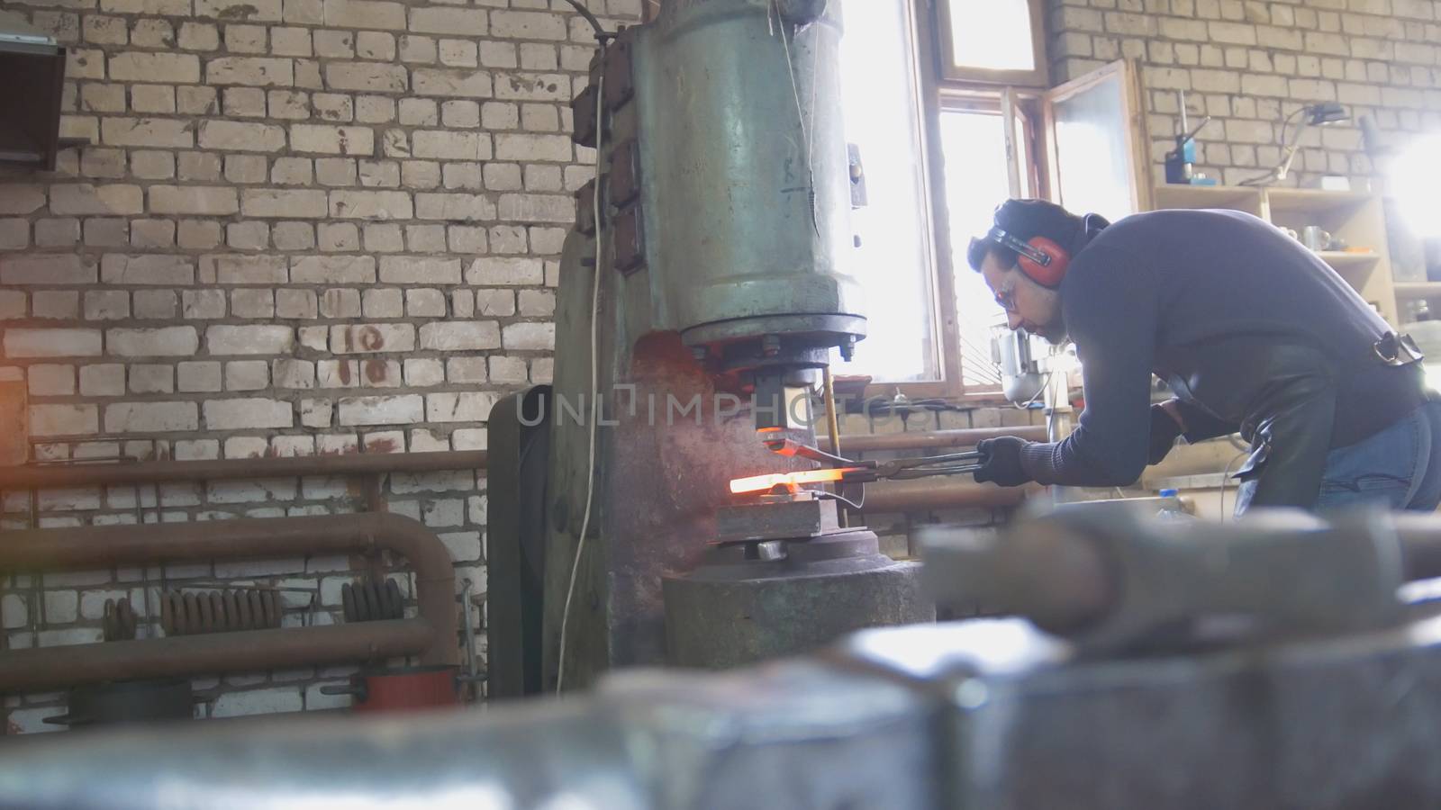 Molten metal is processed under pressure in the hands of a blacksmith, wide angle by Studia72