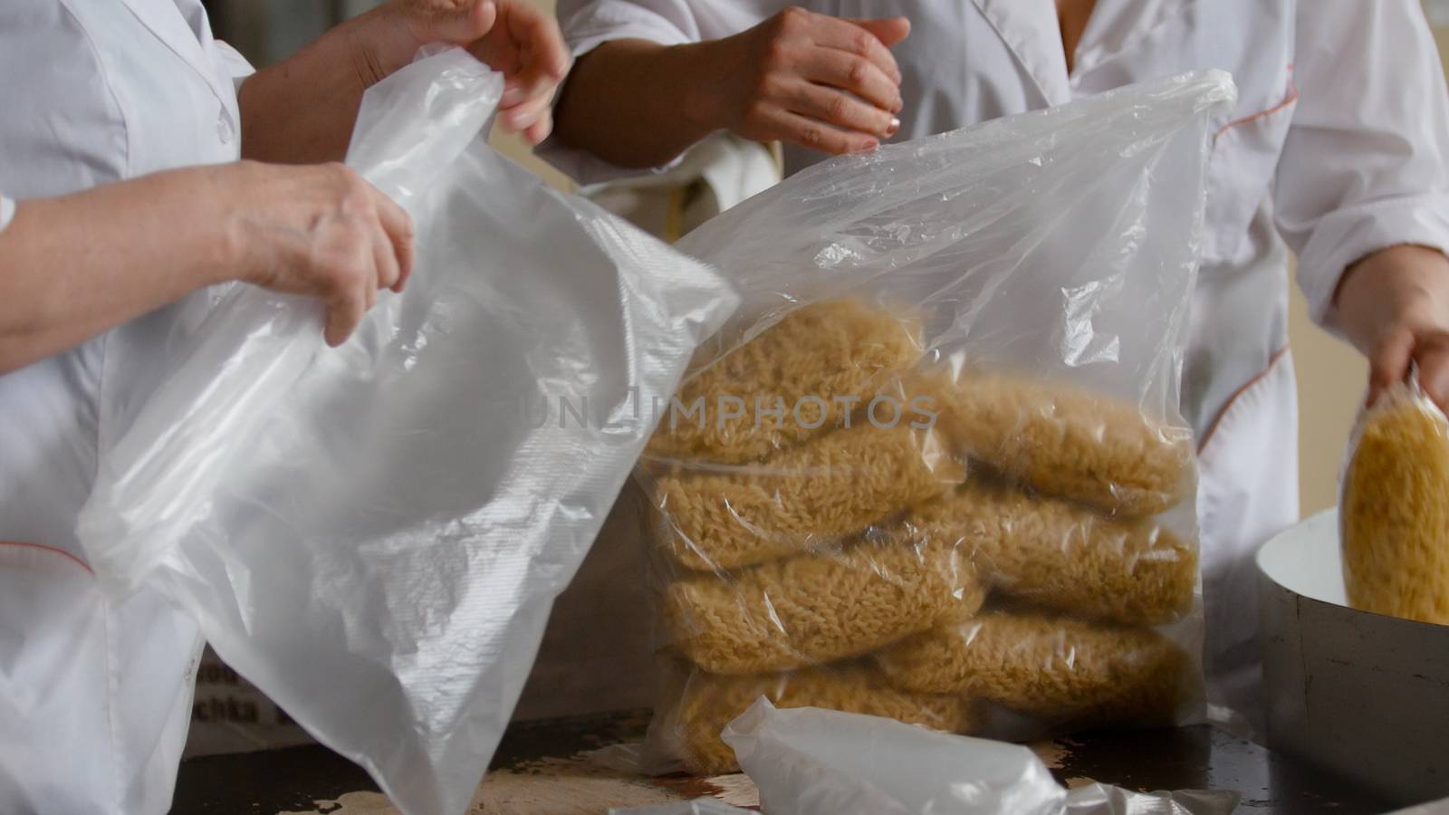 Workers packaging raw macaroni from the production line in a pasta manufactury, telephoto shot