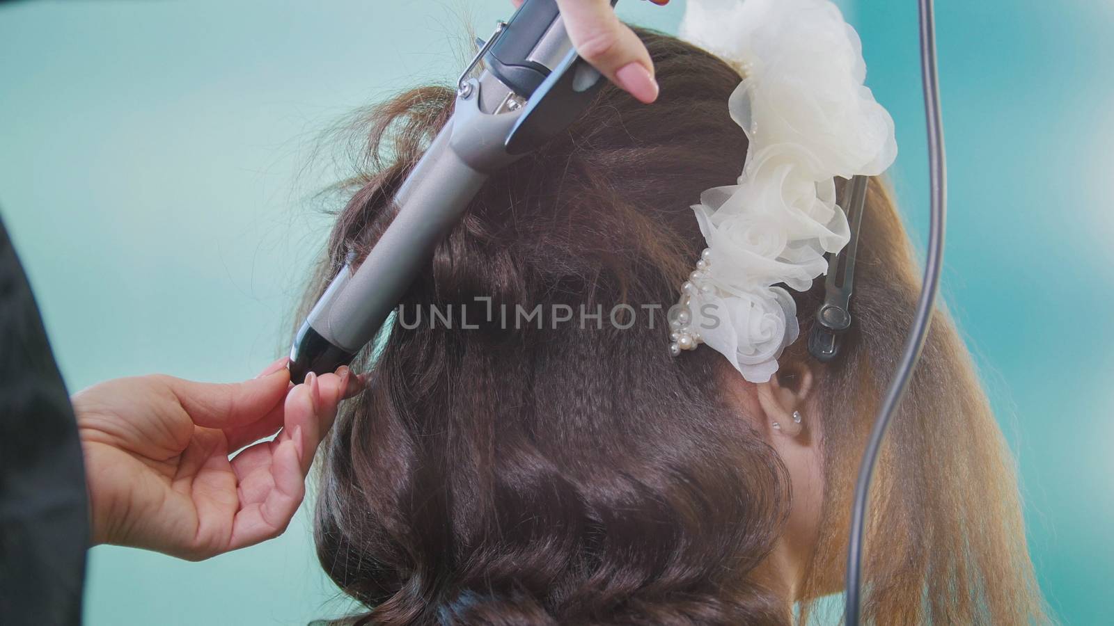 Professional hairstylist making curly hair for beautiful woman, close up