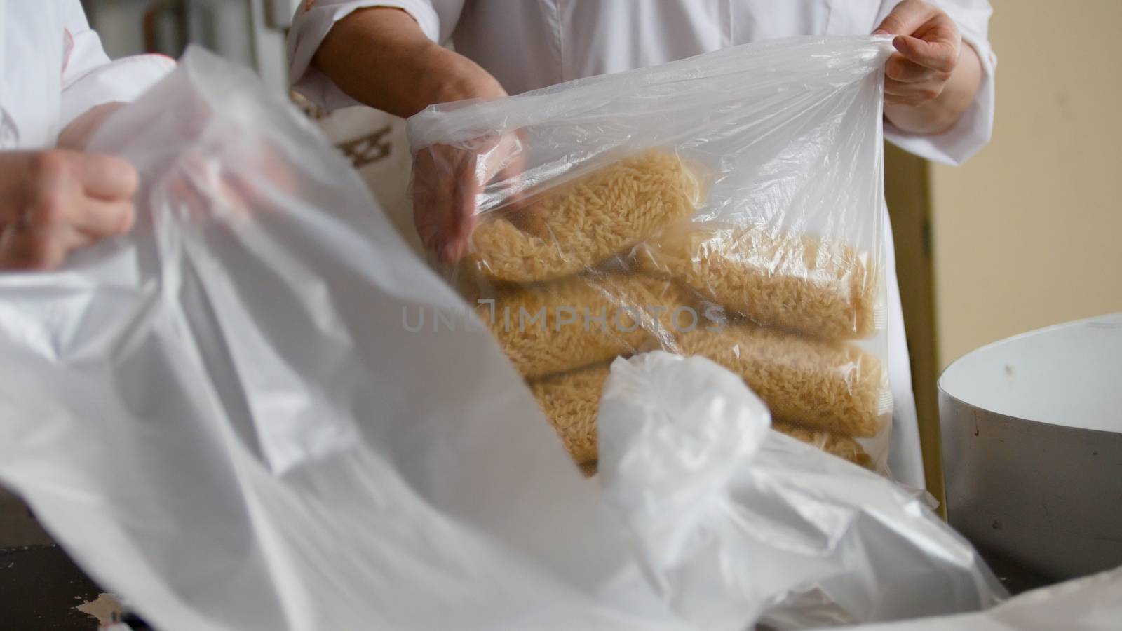 Worker packaging macaroni from the conveyor belt in a pasta factory, close up