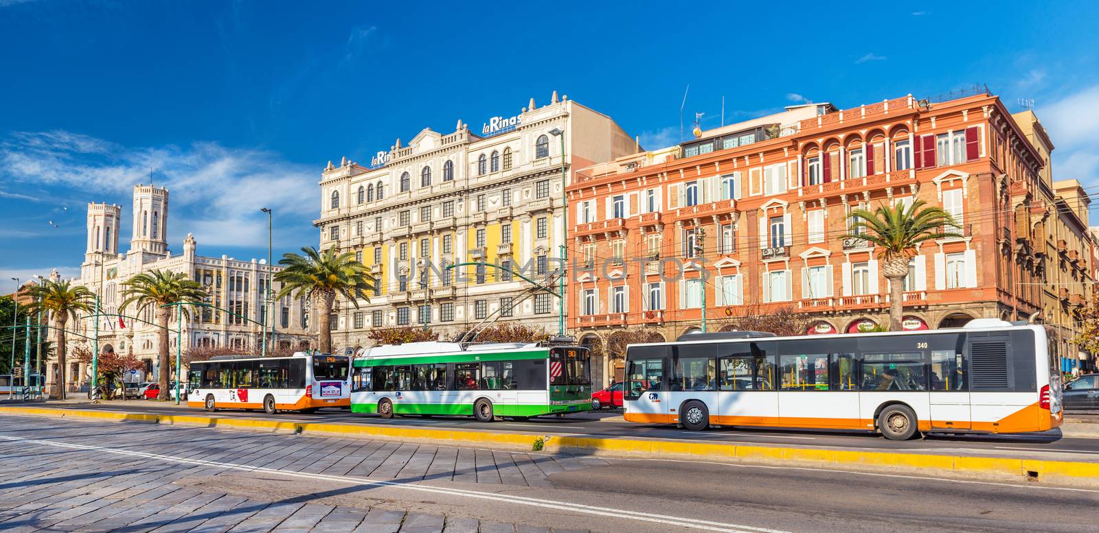 Cagliari, Sardinia - January 2016, Italy: Beautiful colorful buildings on Cagliari seafront, buses and trolley car parked near bus stop on the central street of the city