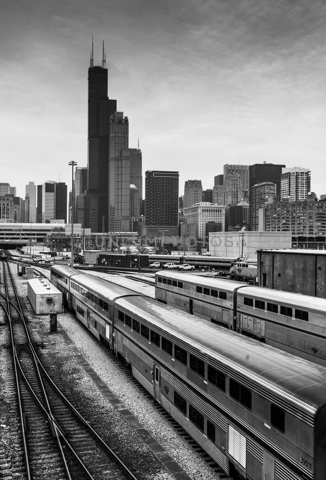 Chicago - March 2017, IL, USA: Chicago skyline at cloudy day. Railroad tracks with train, office buildings in downtown and the Willis (Sears) Tower.