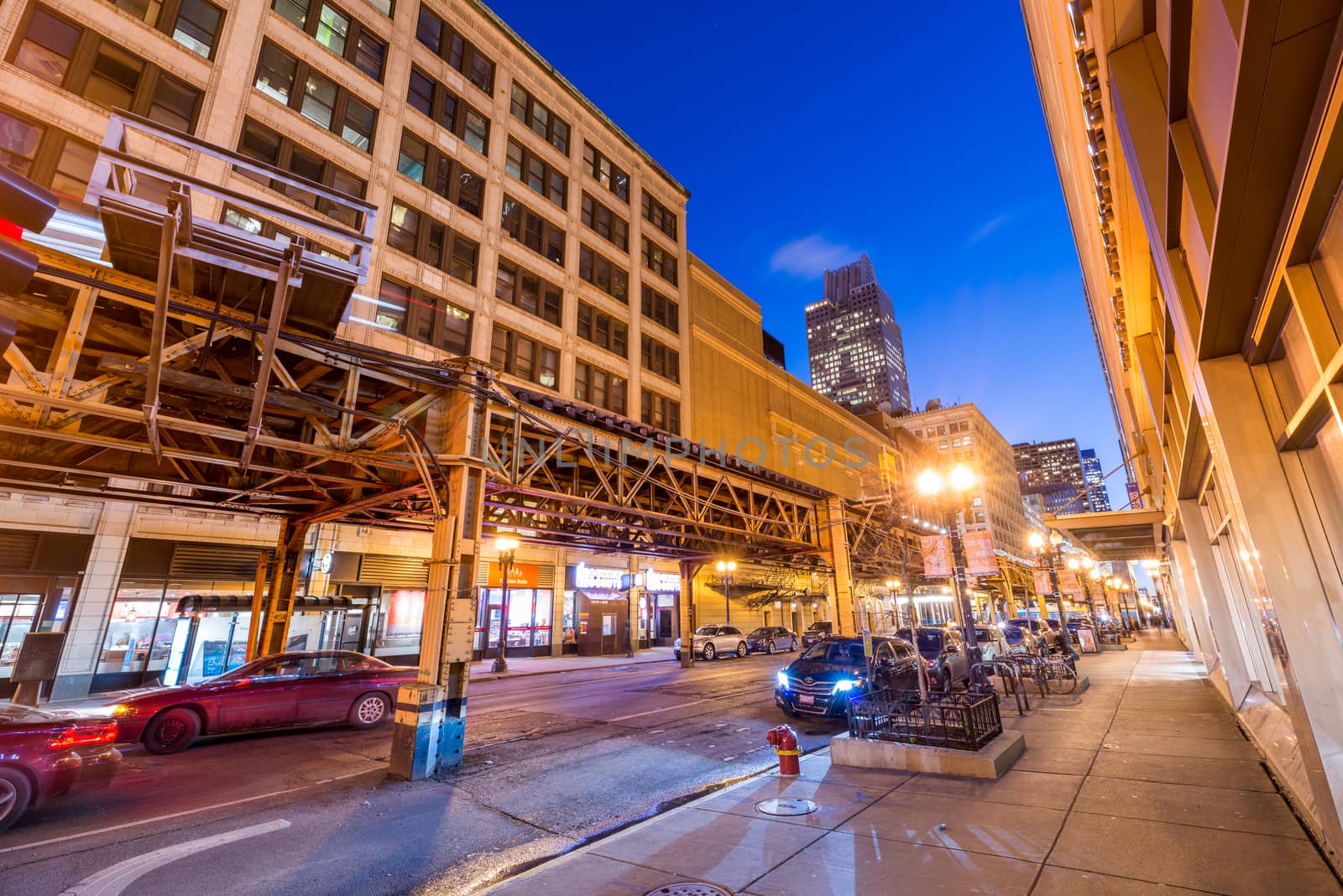 Chicago - March 2017, IL, USA: The street in downtown Chicago at night. Metro ways with passing train and cars moving under them. Wide angle view, long exposure photography