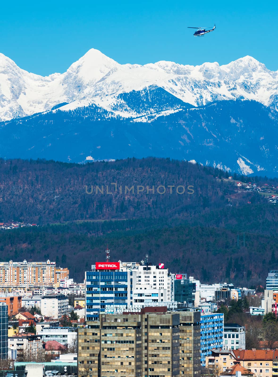 Ljubljana - March 2017, Slovenia: Ljubljana cityscape with snowy mountains on the background and police helicopter flying in the sky