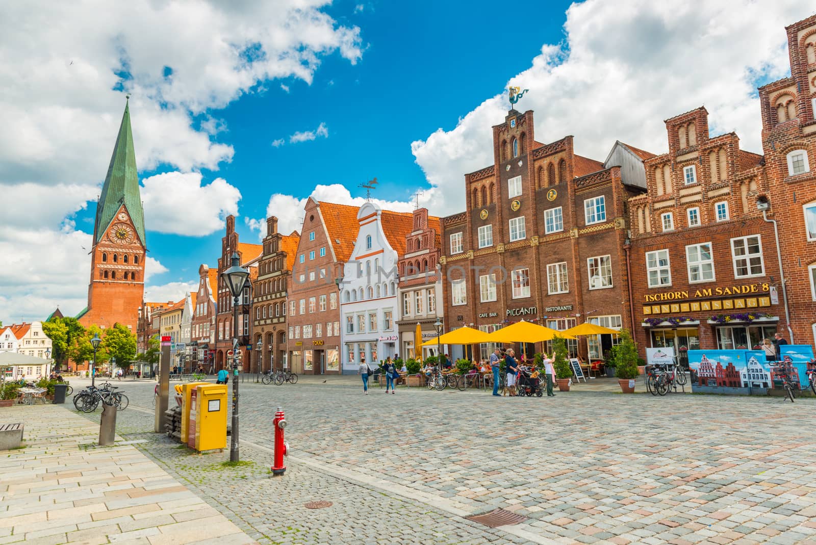 Luneburg - July 2018, Germany: View of the central street with old brick houses, bar, cafe, shops and walking people
