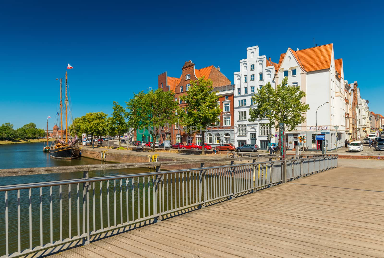 Lubeck (Lübeck) - July 2018, Germany: Cityscape of the old European city with historic buildings, wooden ship and bridge across the Trave river