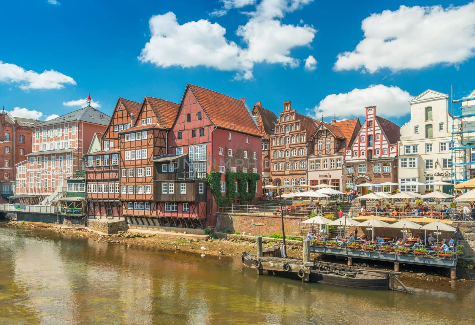 Luneburg - July 2018, Germany: View of the embankment with old historical houses in traditional German architecture style. Colored residential buildings with triangle roofs and Ilmenau river