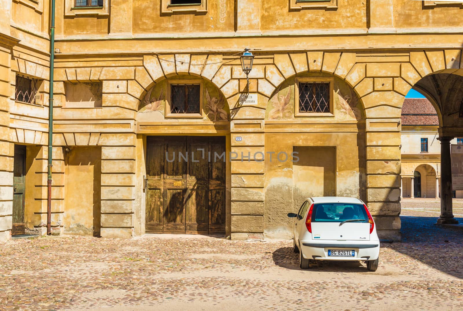 Mantova (Mantua) - July 2017, Italy: Small white car parked near the historical building of the Ducal Palace on the Square of Santa Barbara