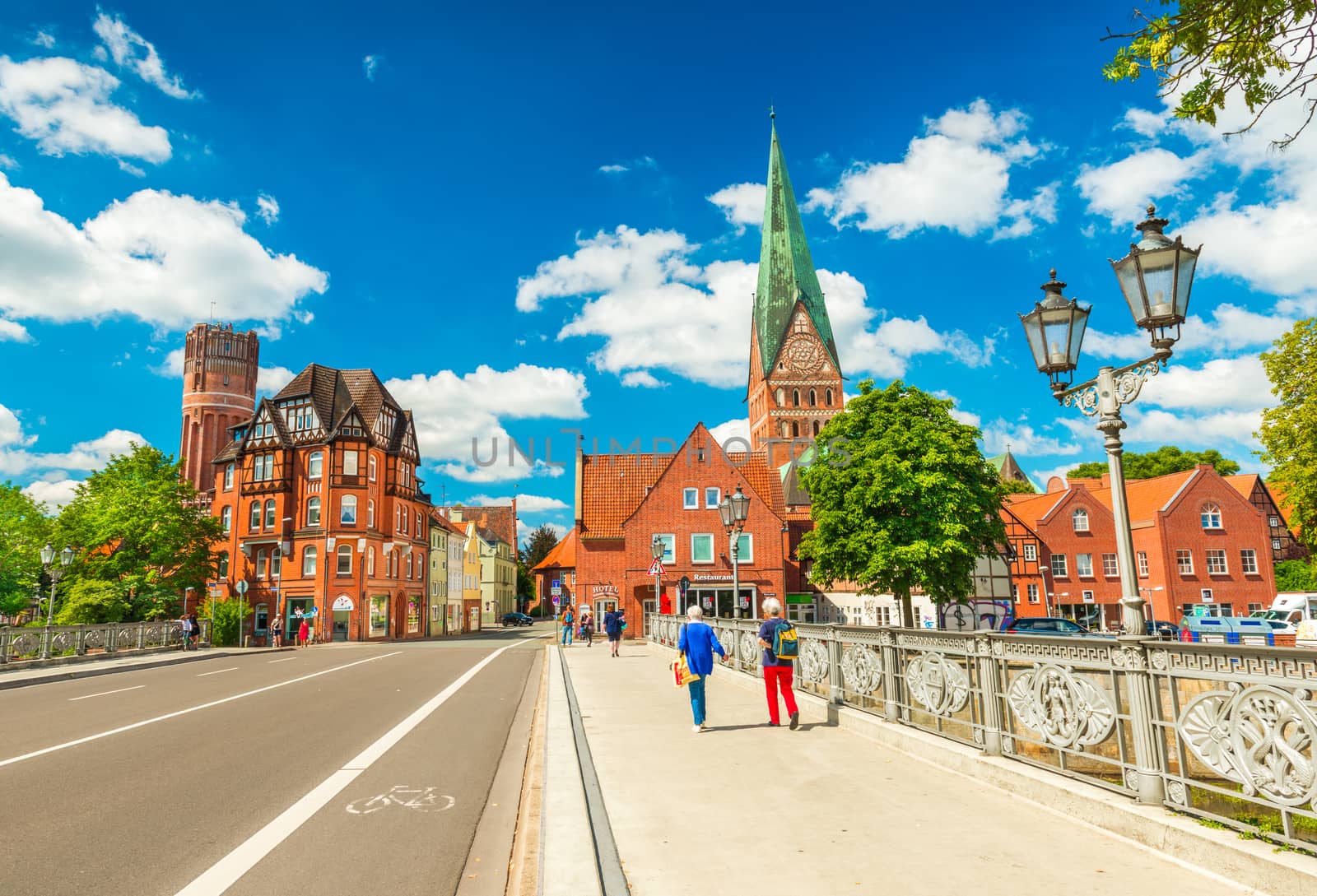 Luneburg - July 2018, Germany: Two women are walking on the bridge across the river. Cityscape of an old European city with traditional architecture