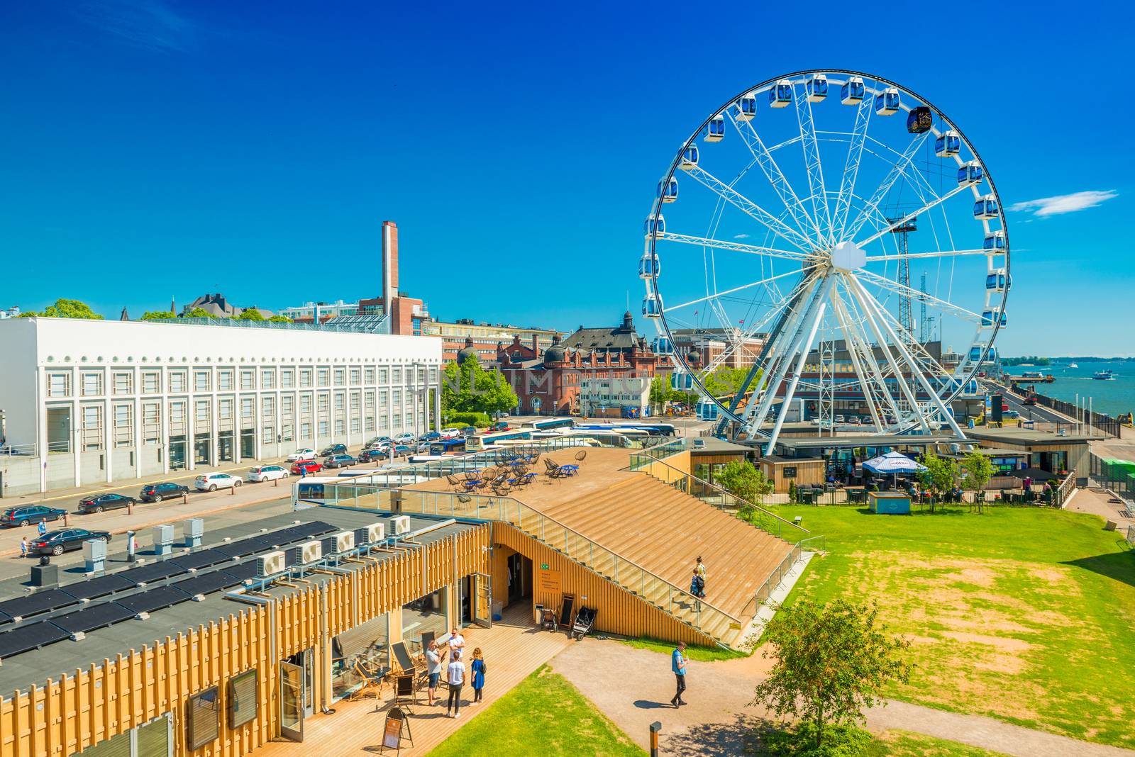 Helsinki - June 2019, Finland: Cityscape of Finnish capital with a ferris wheel, modern architecture and walking people on a sunny summer day