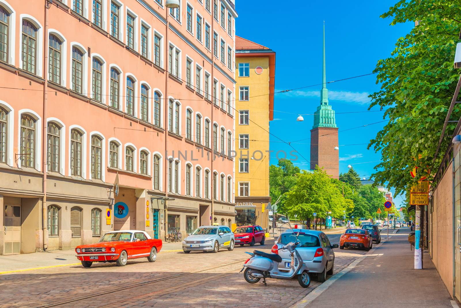 Helsinki - June 2019, Finland: A street with a car traffic, Mikael Agricola Church and colorful residential buildings