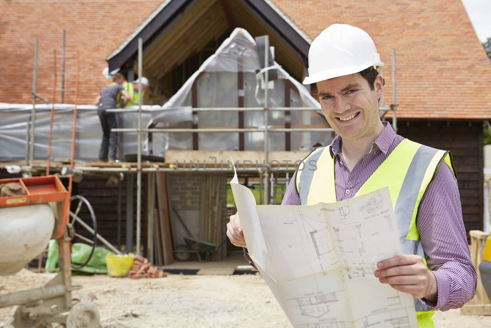 Architect On Building Site Looking At House Plans by HWS