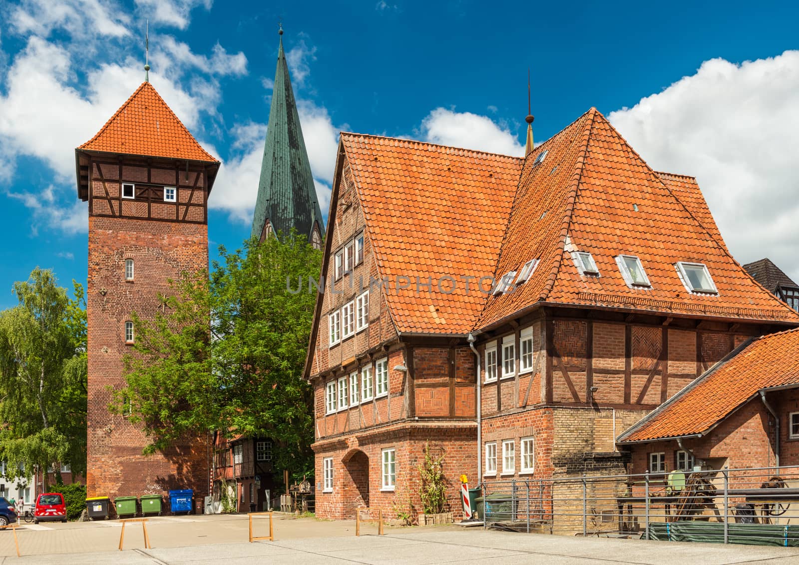 Luneburg - July 2018, Germany: Historical buildings in the traditional German architecture style. Old house and tower made of red brick on a street of popular touristic town