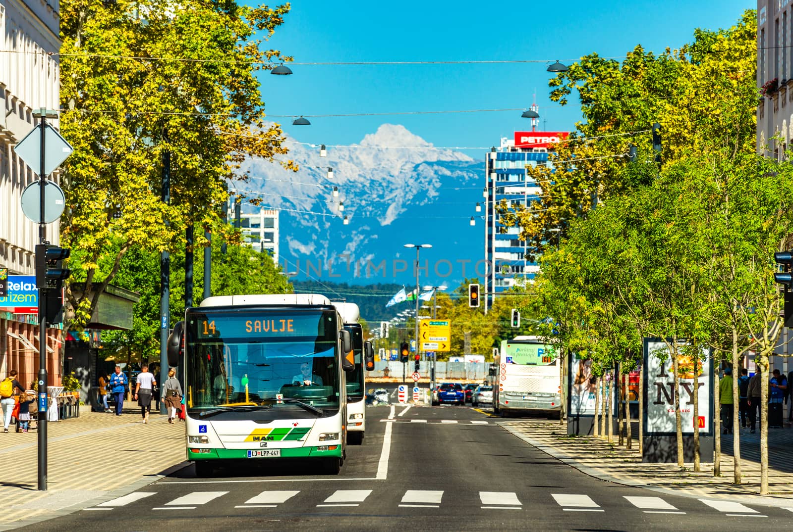 Ljubljana - September 2019, Slovenia: View of a street with public transport, crosswalk, modern architecture and the snowy Alps in the background