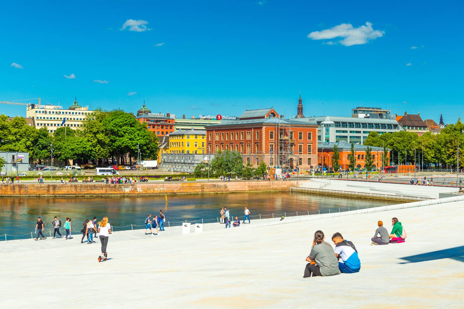 Oslo - June 2019, Norway: View of an embankment in the central part of Oslo. Cityscape with people walking near the Opera House