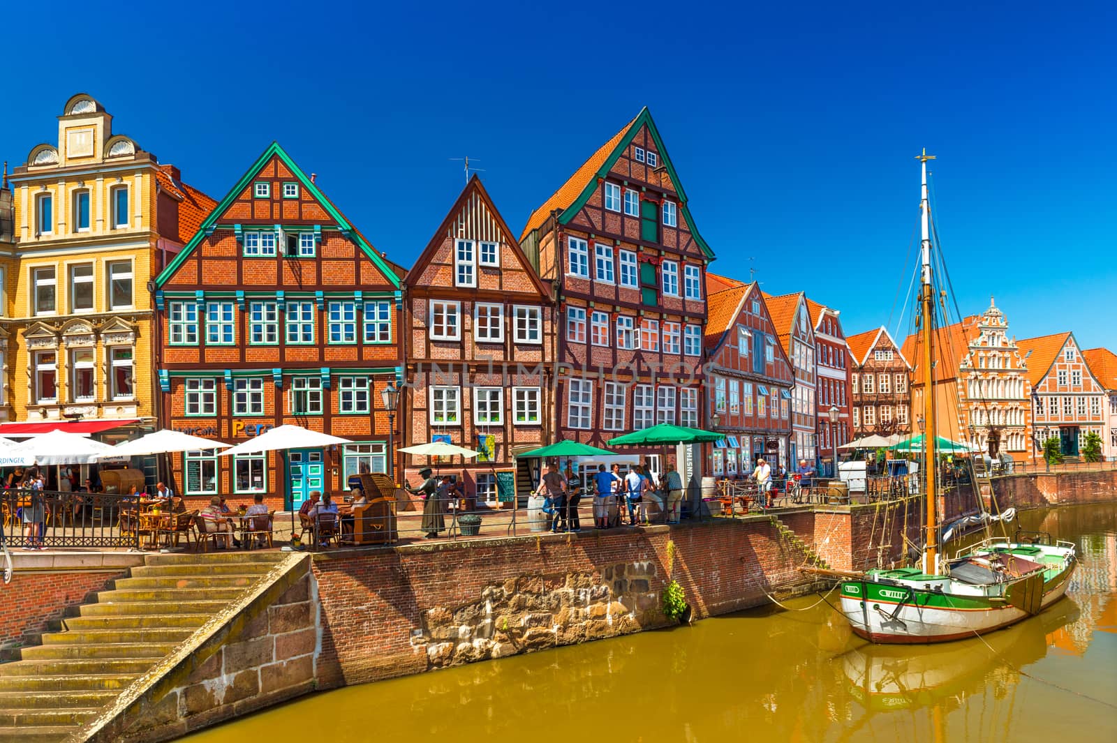 Stade - July 2019, Germany: Cityscape of a small, beautiful German town with the traditional half-timbered architecture and canal with an old wooden sailboat