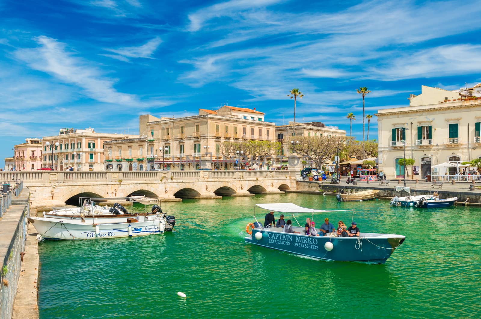 Syracuse - May 2019, Italy: Cityscape of Ortygia with Umbertino Bridge (Ponte Umbertino), old historical buildings and a boat with tourists