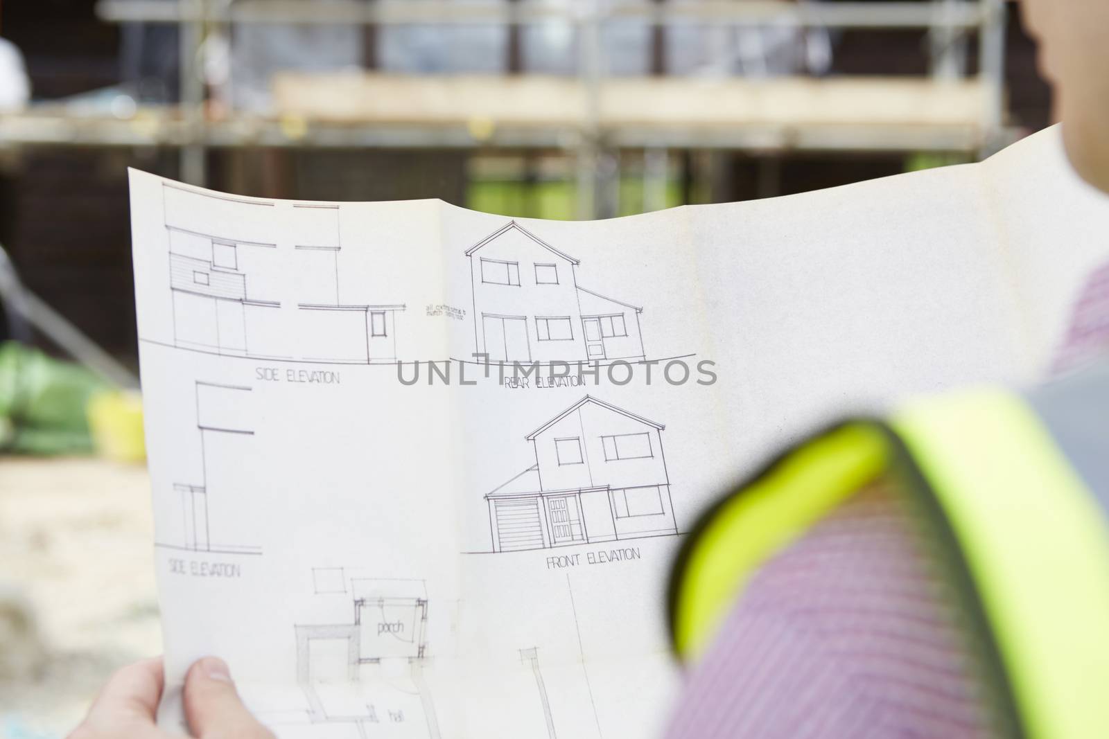 Architect On Building Site Looking At Plans For House