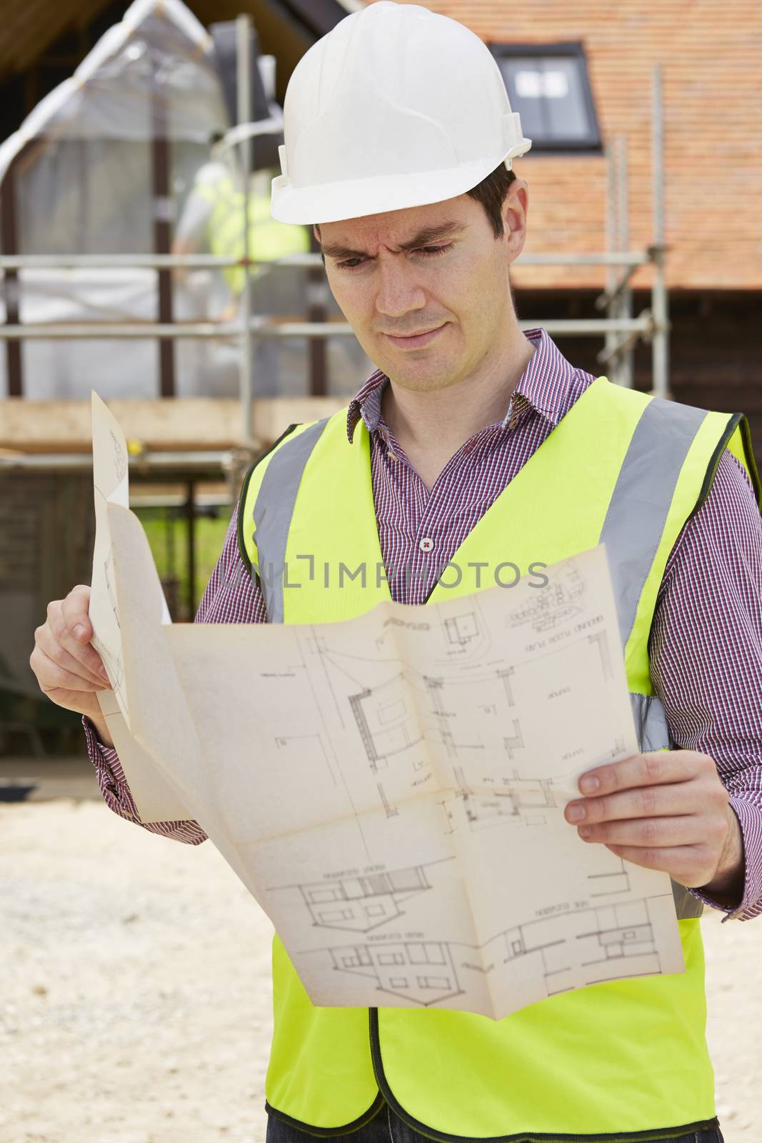 Architect On Building Site Looking At Plans For House by HWS