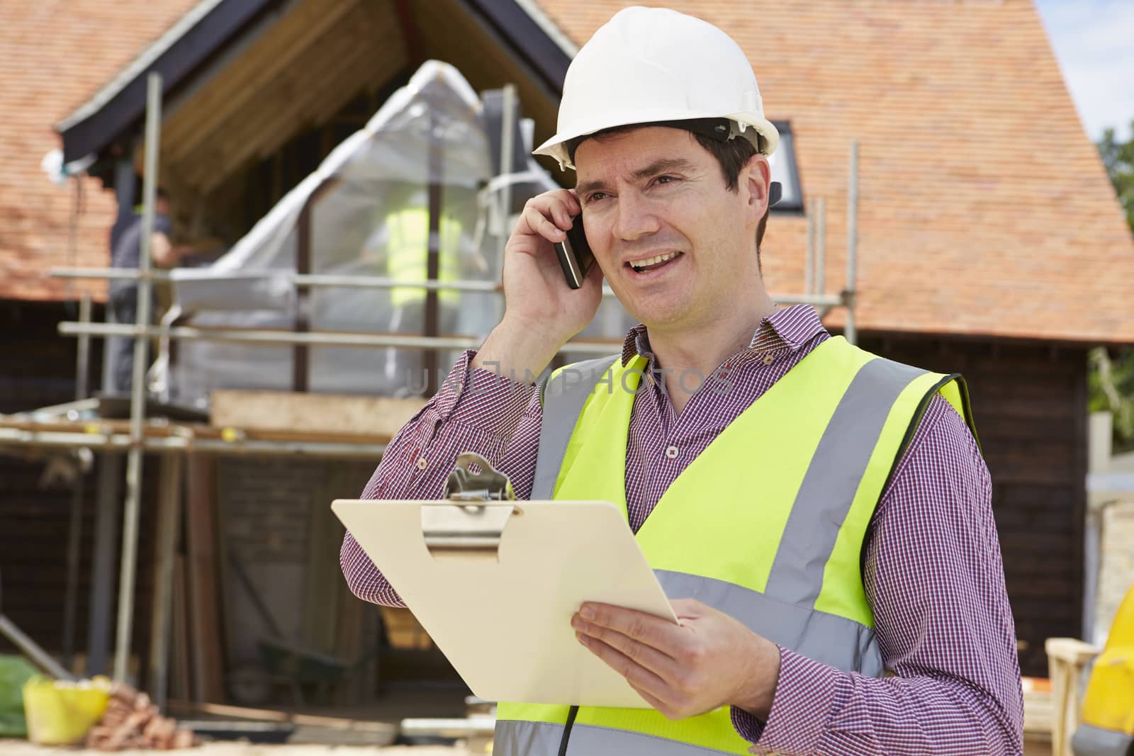 Architect On Building Site Using Mobile Phone by HWS