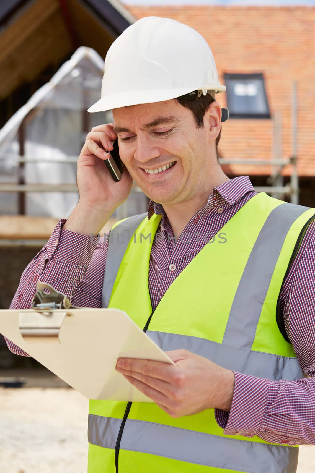 Architect On Building Site Using Mobile Phone by HWS